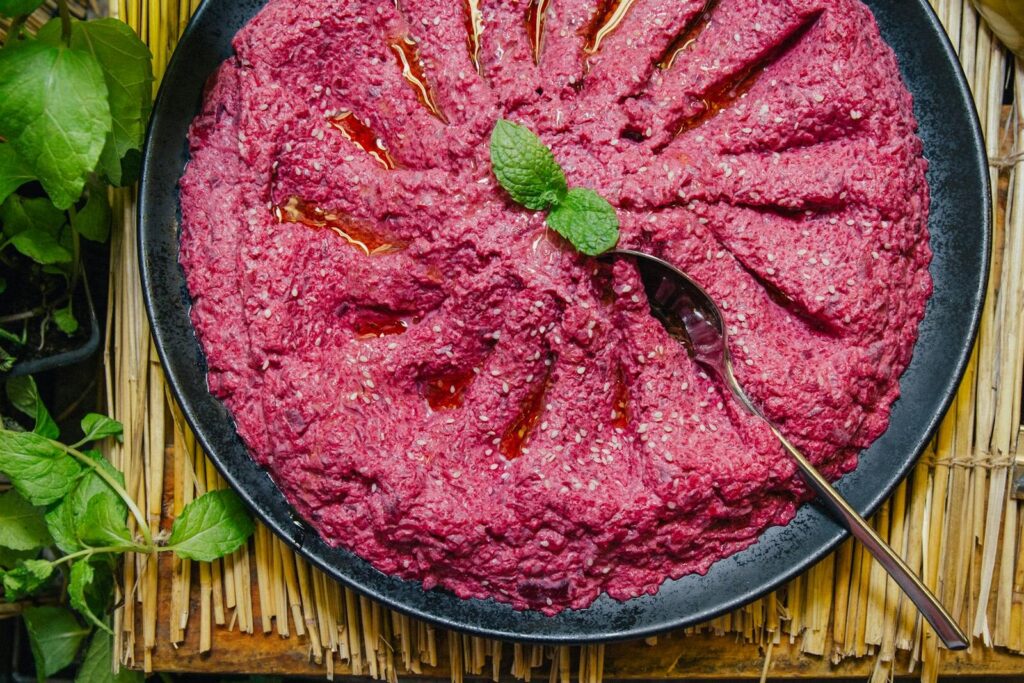 Top view of a delicious beet hummus garnished with mint, perfect for a healthy snack.